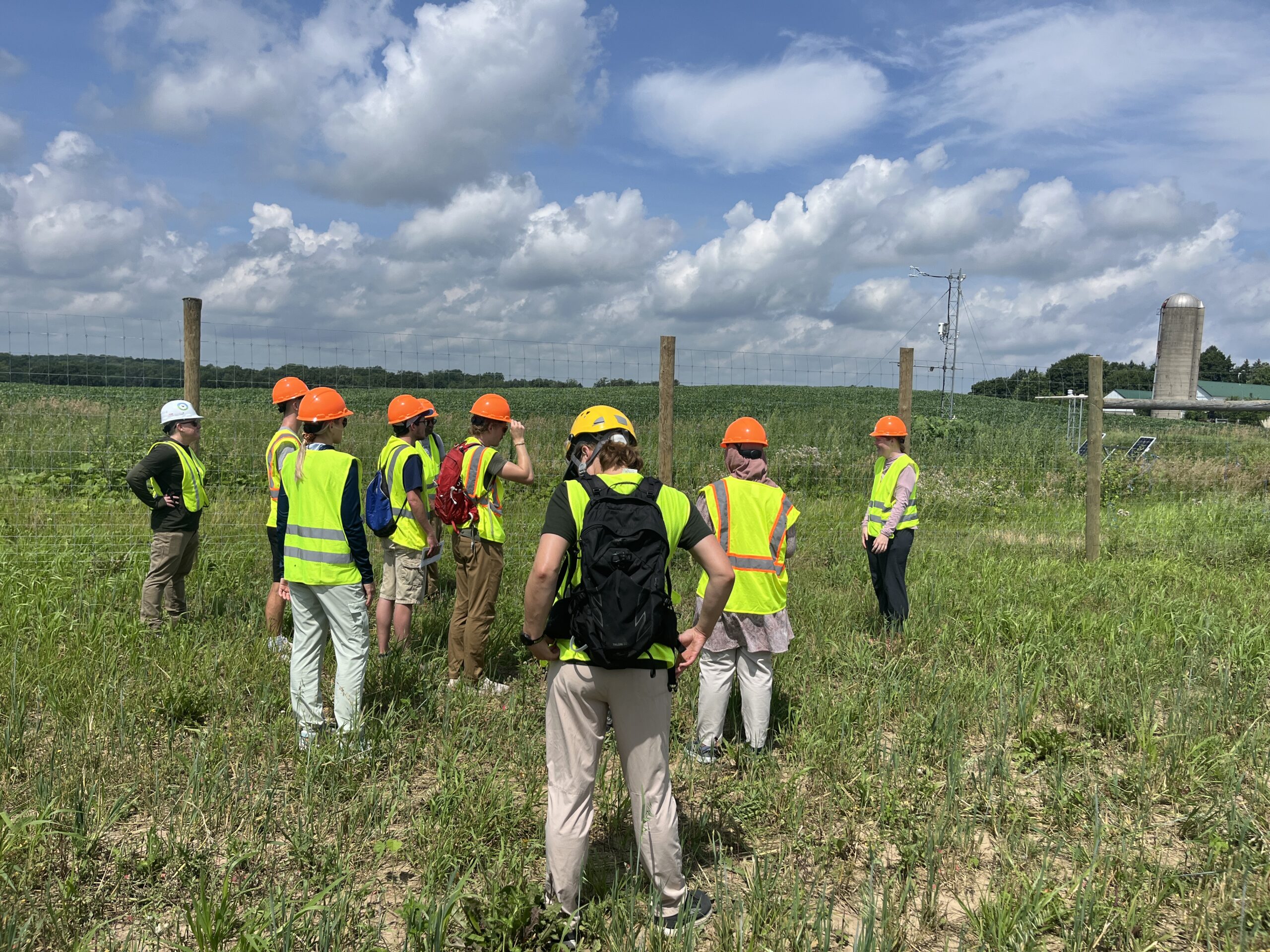 Students in safety gear touring agrivoltaic solar site near measurement tower
