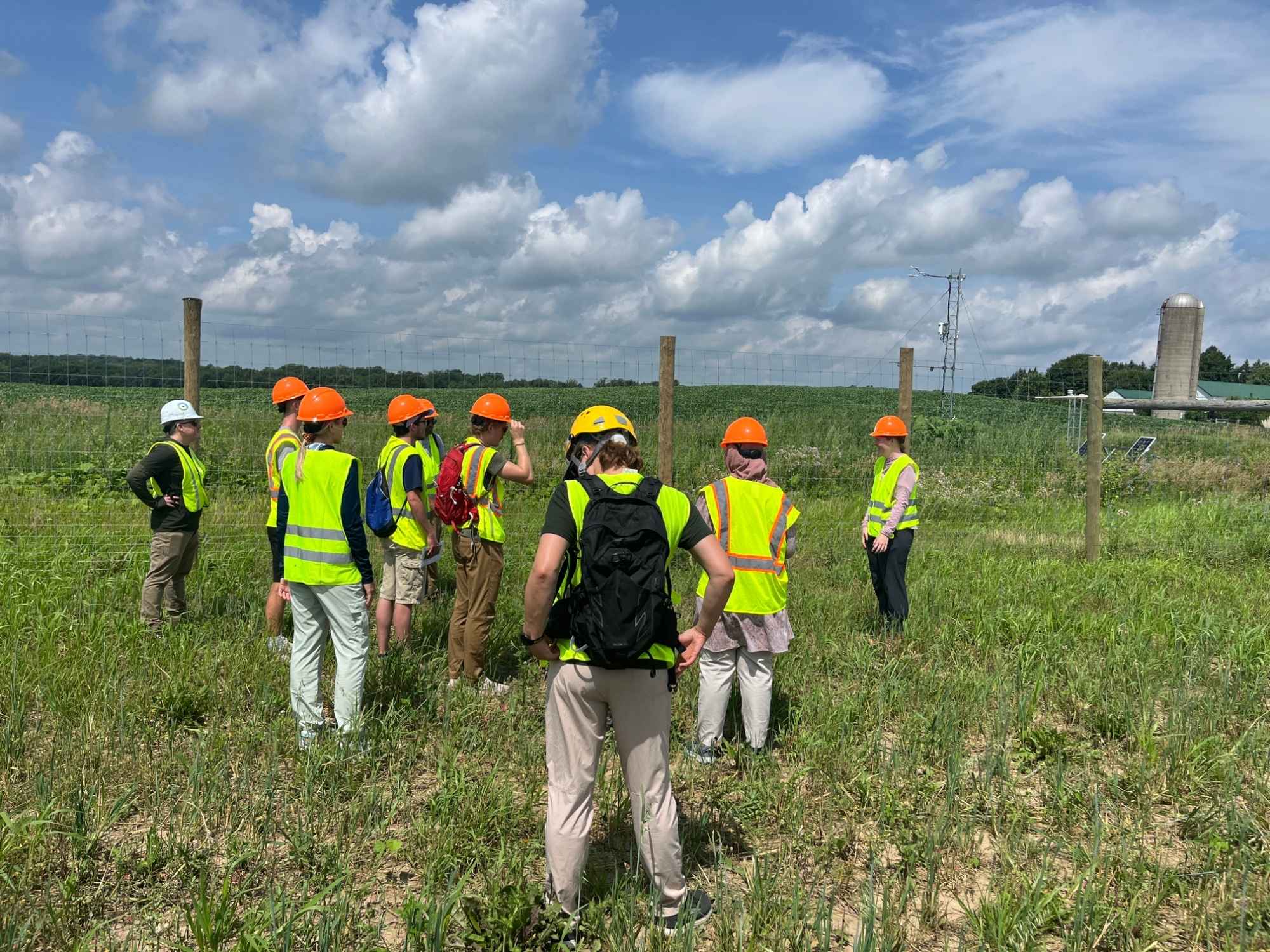 Students in safety gear touring agrivoltaic solar site near measurement tower